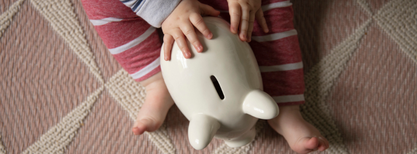 Baby is sitting with piggy bank to save money